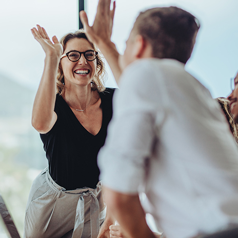 Businesswoman giving a high five to male colleague in meeting. Business professionals high five during a meeting in boardroom.